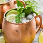 moscow mule with gin in copper mug garnished with mint and lime