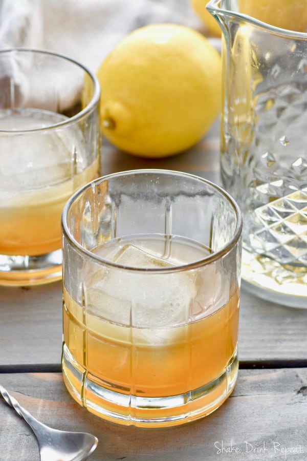 two gold rush cocktails in glasses with giant ice cubes