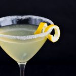 front view of martini glass rimed with sugar and lemon curl and filled with lemon drop martini