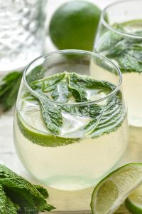 glass of mojito sangria cocktail with mint and limes