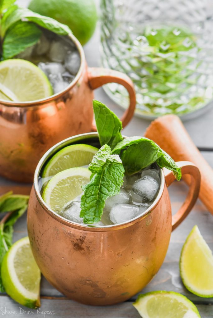 moscow mule with gin in copper mug garnished with mint and lime