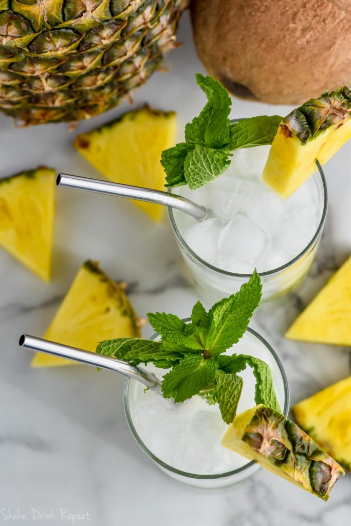 overhead view of two pina colada mojitos garnished with fresh mint and fresh pineapple