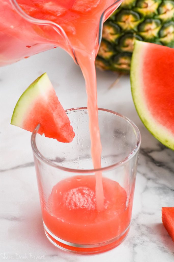 pouring watermelon rum punch into a glass