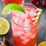 overhead view of an ice filled glass full of red cherry lime vodka tonics