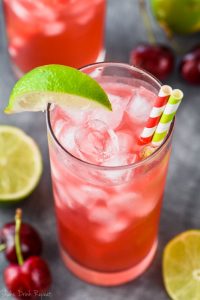 overhead view of an ice filled glass full of red cherry lime vodka tonics