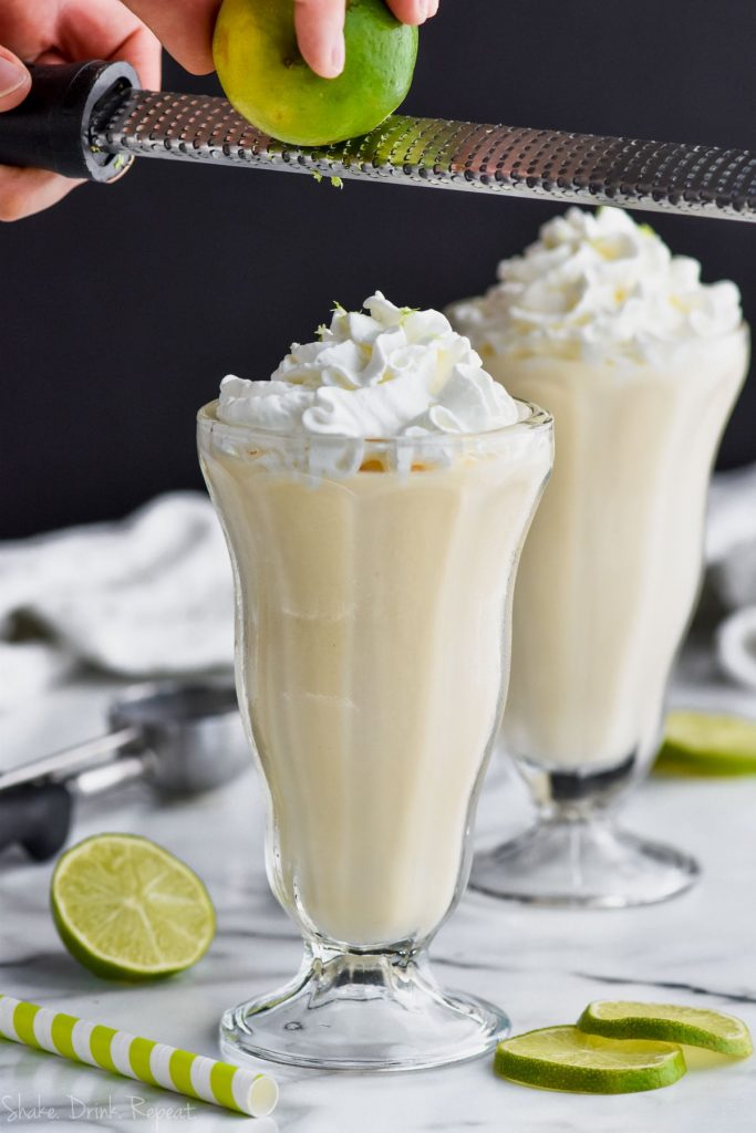 zesting a lime onto whipped cream on a margarita milkshake