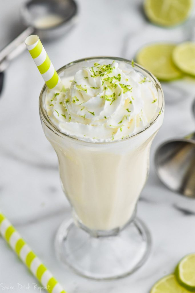 overhead view of margarita milkshake with straw, whipped cream, and lime zest