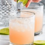 squeezing limes into a paloma cocktail