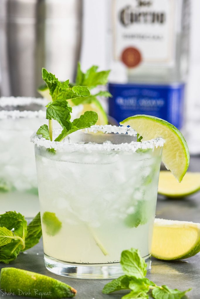 a mojito margarita in a salt rimmed glass with fresh mint and a lime wedge