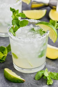 a mojito margarita in a salt rimmed glass with fresh mint and a lime wedge