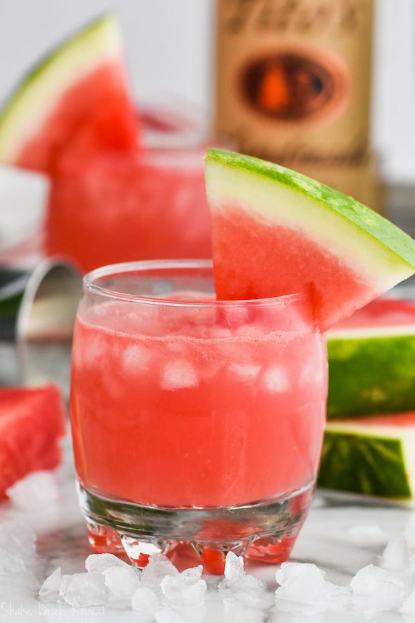 glass of watermelon vodka tonic garnished with a watermelon wedge