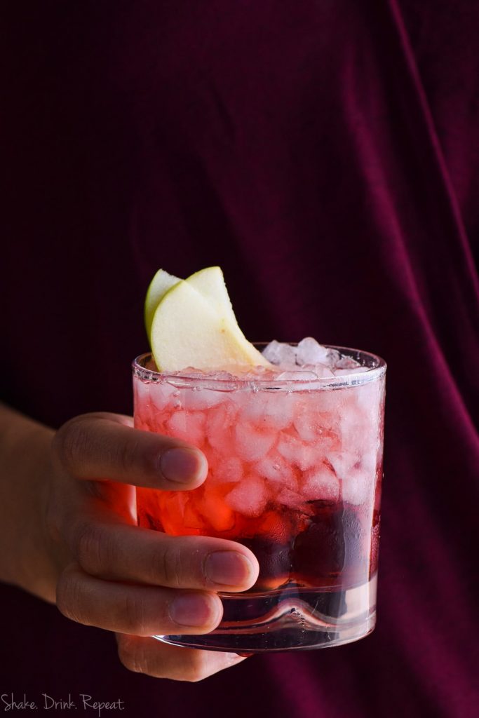 cranberry apple whiskey cocktail garnished with apple