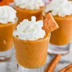 shot glass full of pumpkin pie shot topped with whipped cream