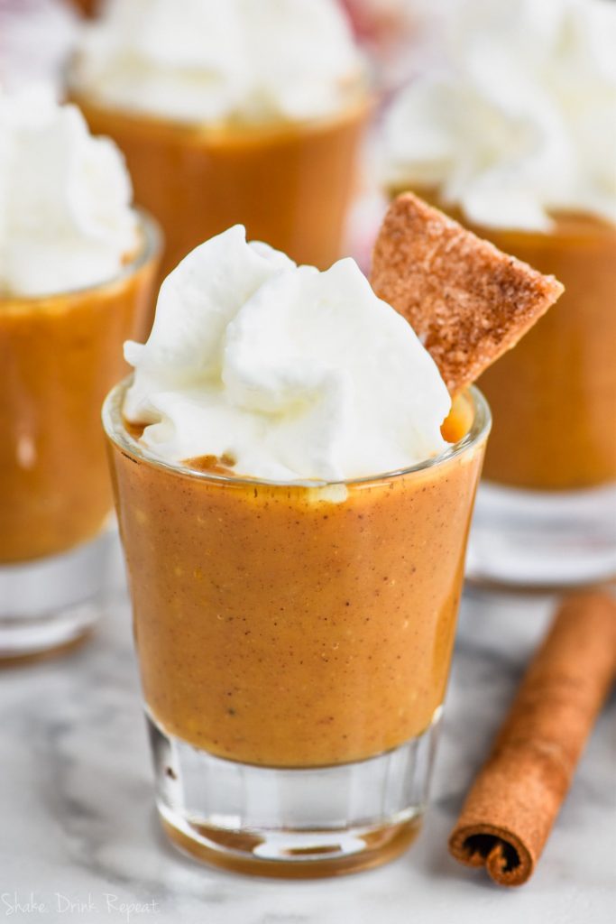 shot glass full of pumpkin pie shot topped with whipped cream