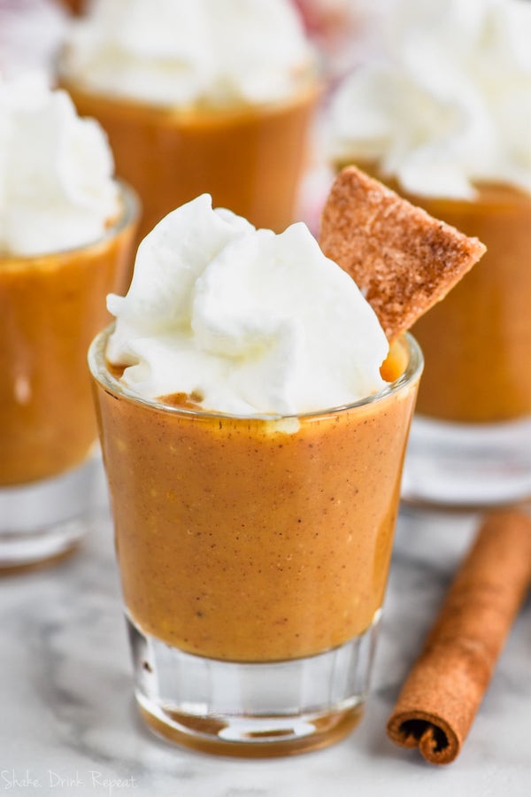 shot glass full of pumpkin pie shot topped with whipped cream