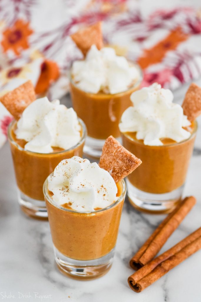 shot glass full of pumpkin pie shot topped with whipped cream