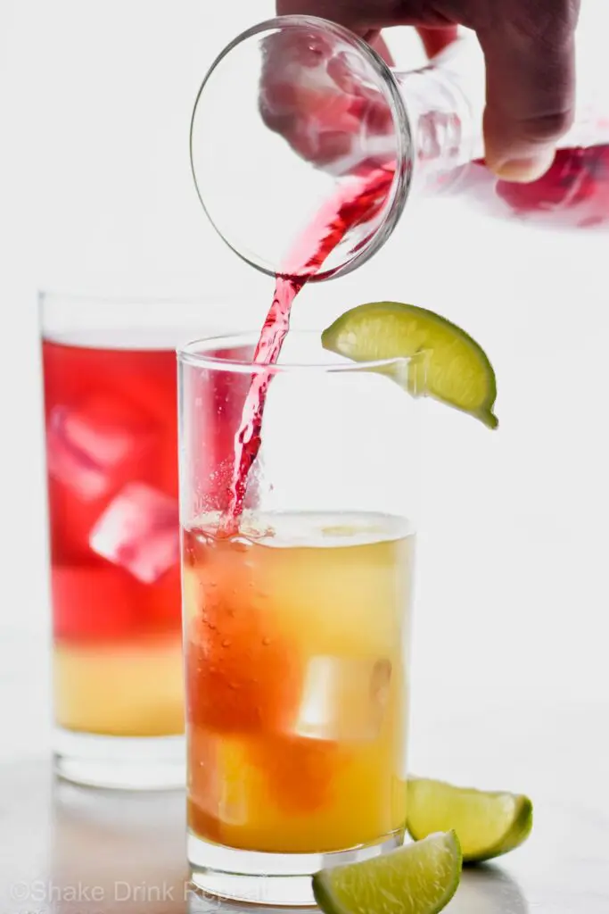 Bay Breeze in a glasses with lime slices and ice and drink being poured into them