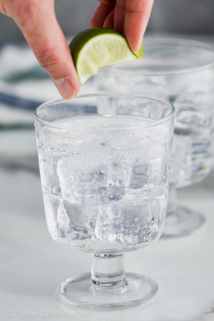 Two glasses of Vodka Press with ice and hand squeezing lime into glass