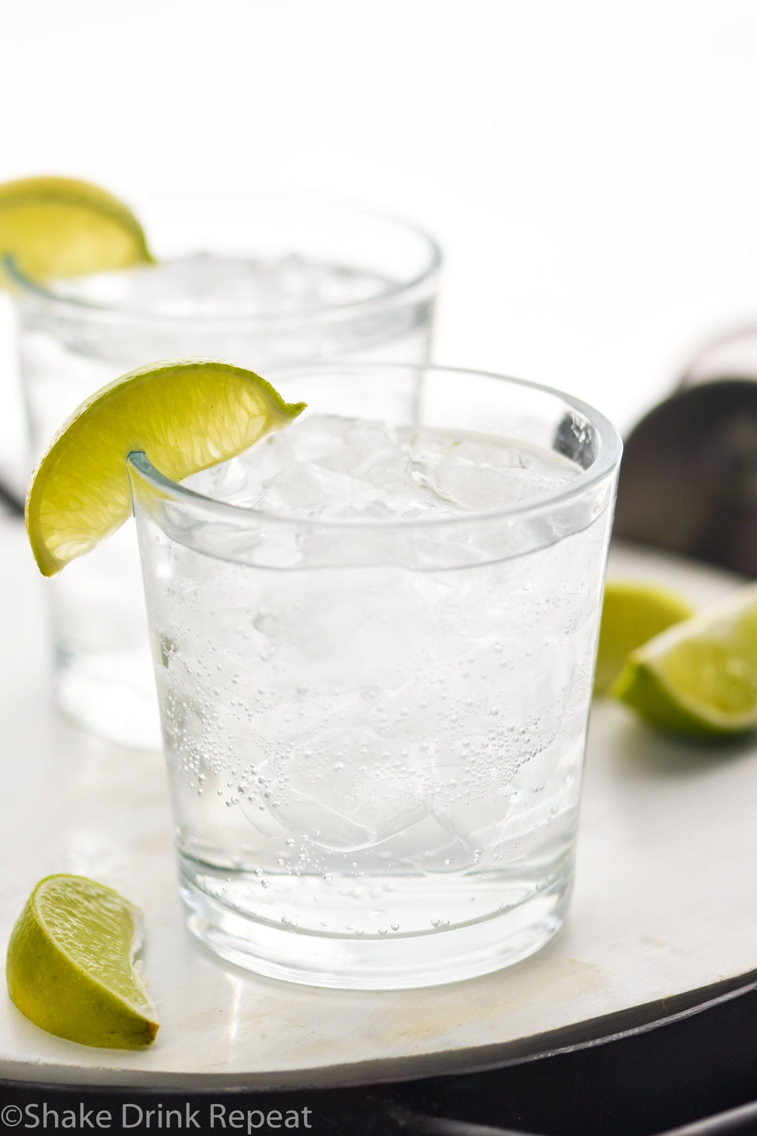 Two glasses of Vodka Soda with ice and lime wedges