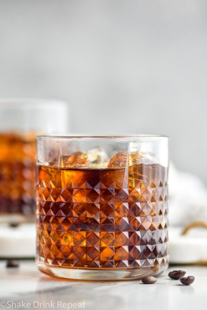 Two glasses of Black Russian with ice, surrounded by coffee beans