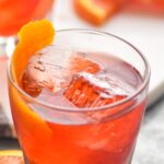 glass of boulevardier cocktail with ice and orange garnish