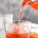 glass of boulevardier cocktail with ice and orange garnish