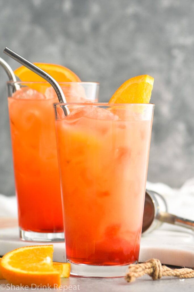 two glasses of garibaldi with ice, straws, and orange garnish