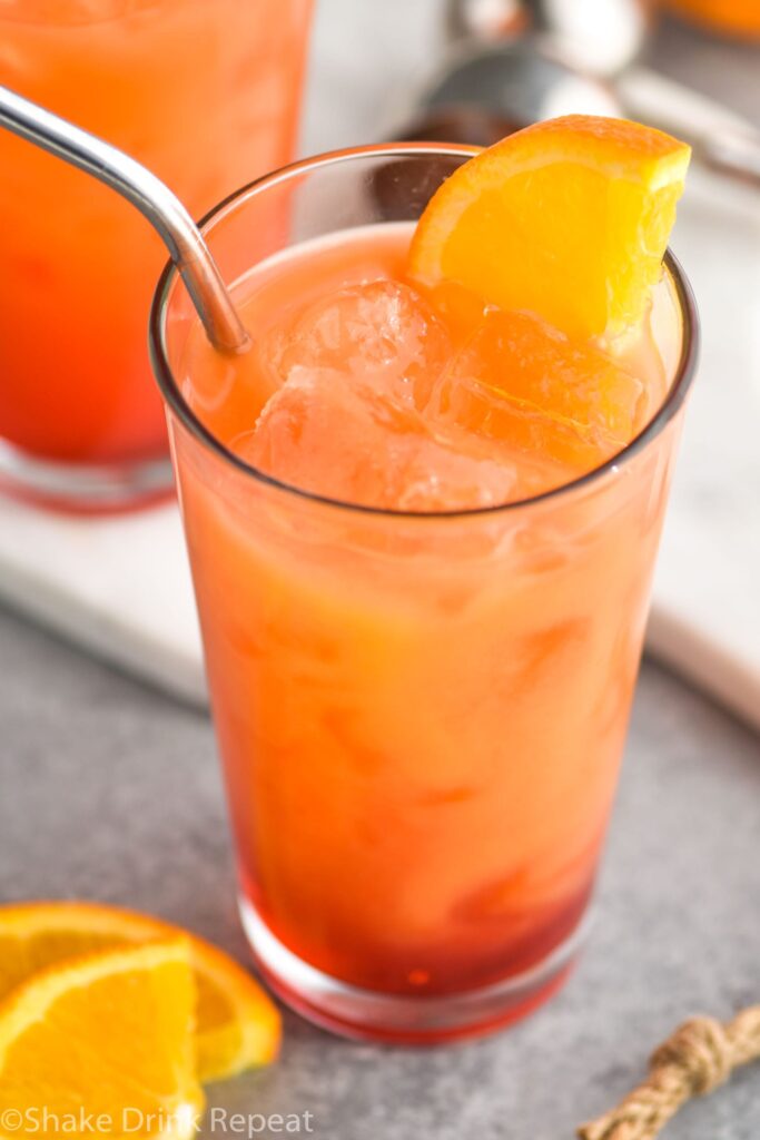 glass of garibaldi cocktail with ice, straw and orange garnish