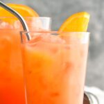 two glasses of Garibaldi cocktail with ice, orange, and straw