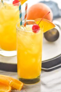 glass of Harvey Wallbanger with straws, orange wedge and cherry garnish