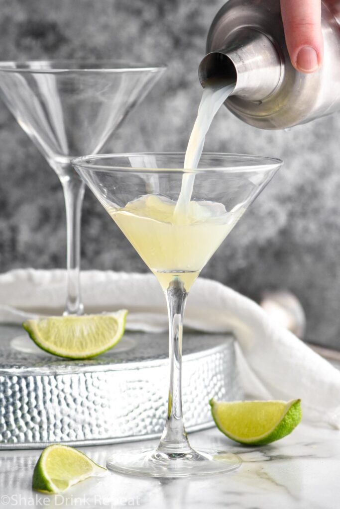 martini glass of Kamikaze Drink being poured with lime wedge garnish