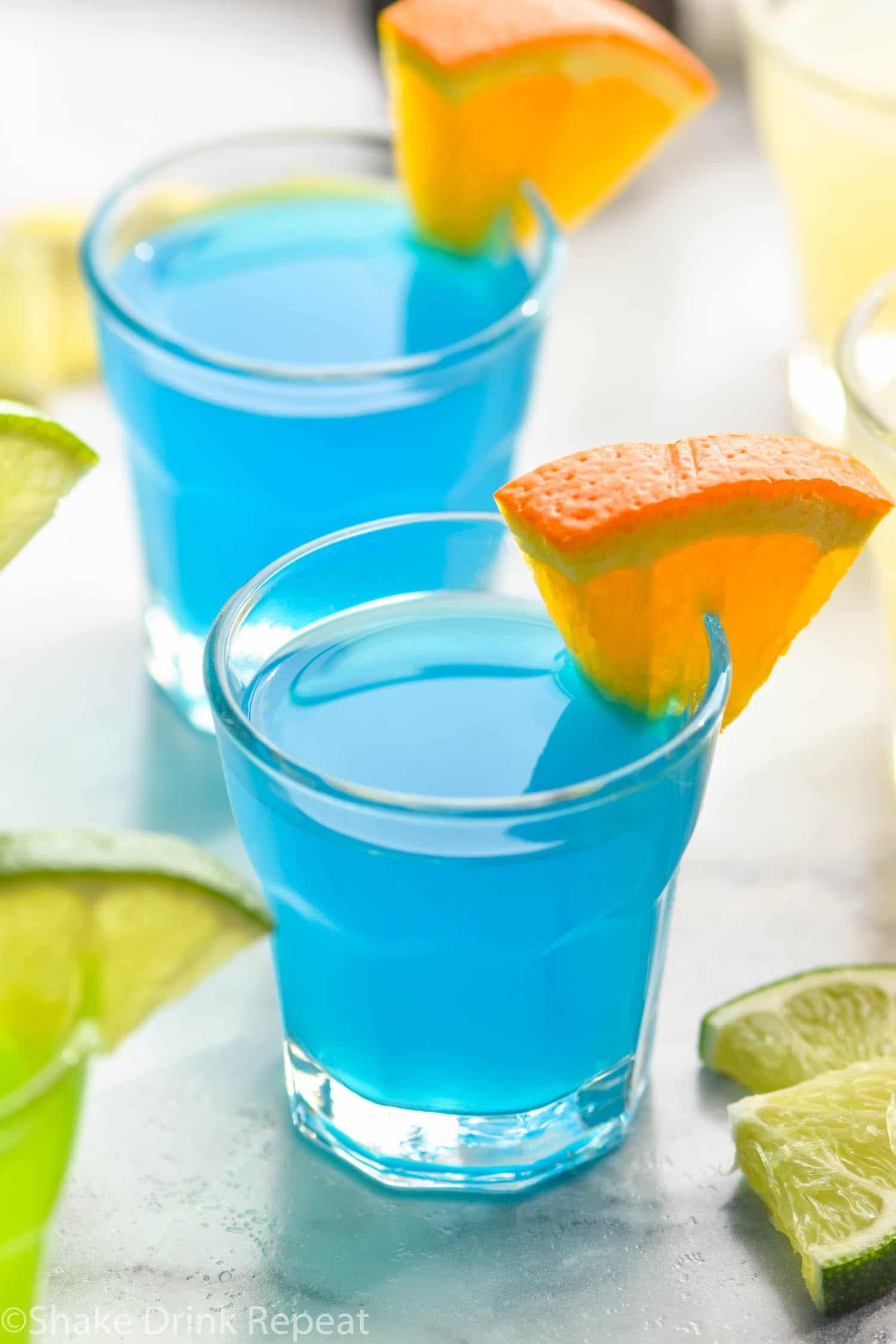shot glass with green and blue kamikaze shot with orange and lime wedge