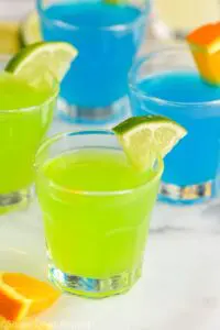 4 kamikaze shots in glasses with lime and orange wedge garnish