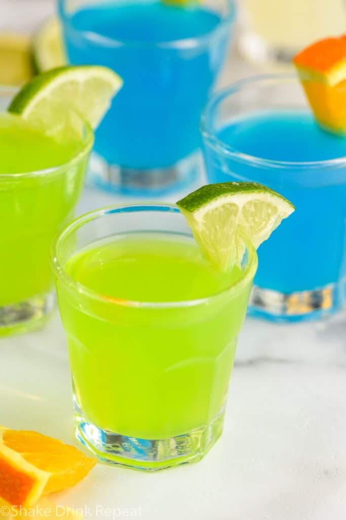 4 kamikaze shots in glasses with lime and orange wedge garnish