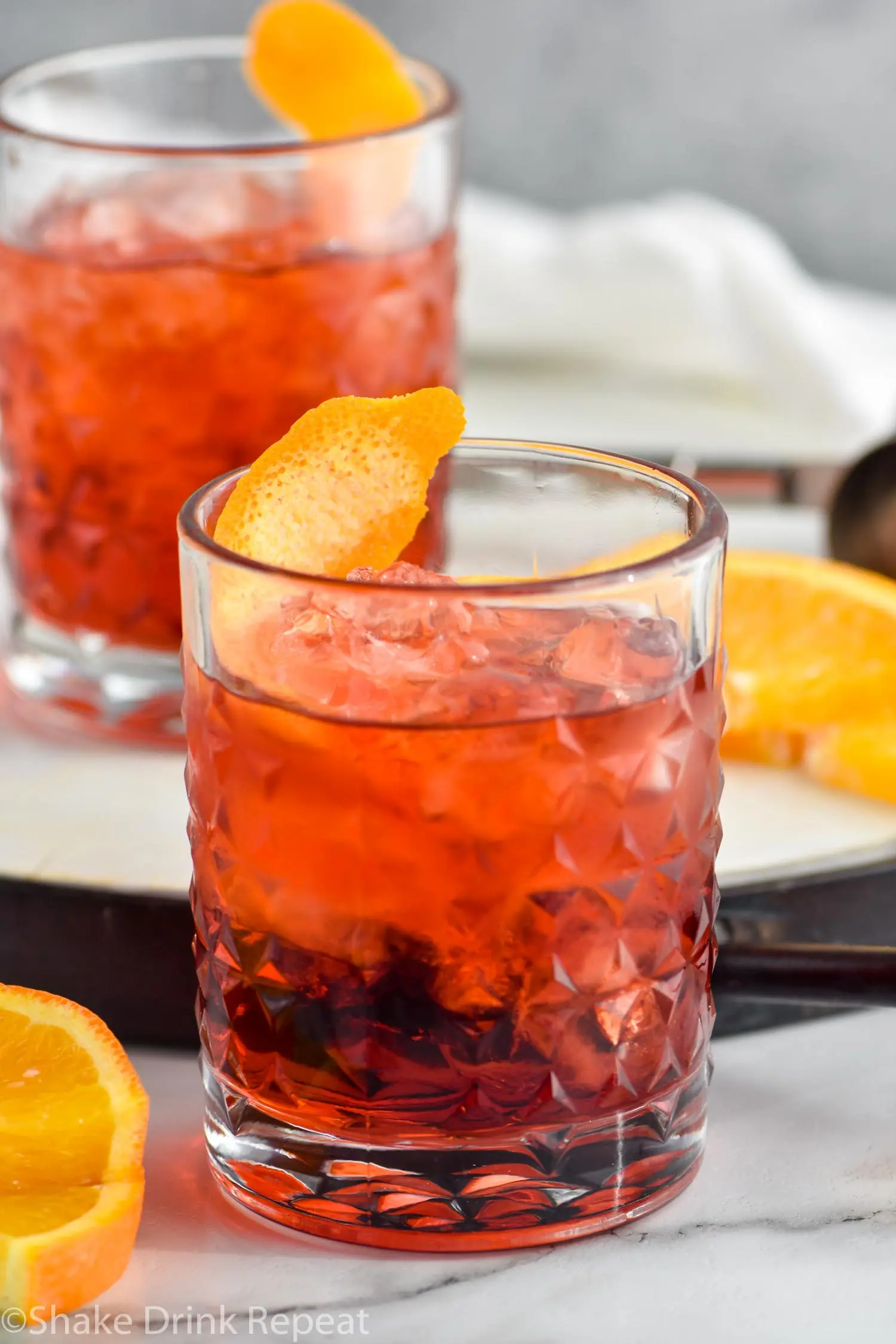 two glasses of Negroni with ice and orange twist