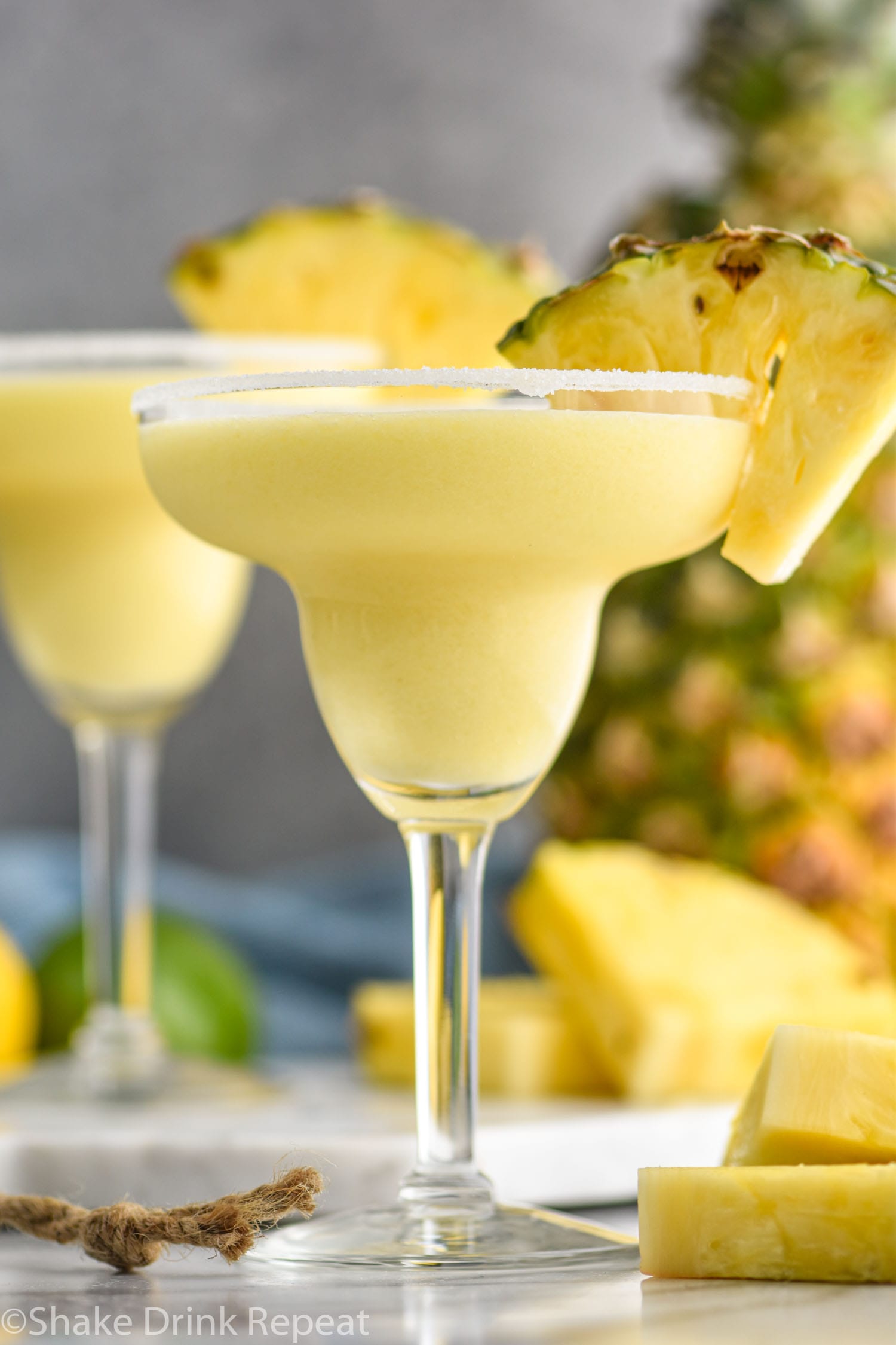 two glasses of pineapple margarita with salted rim