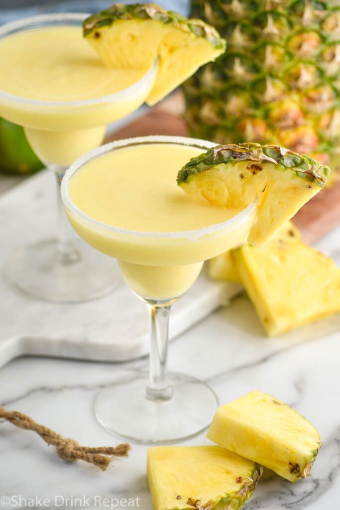 two glasses of pineapple margarita with salted rim