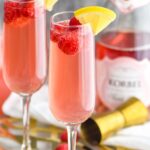 two glasses pink mimosa recipe with ingredients, rosé, raspberries and lemon