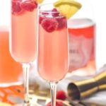 two glasses pink mimosa recipe with raspberries and ingredients