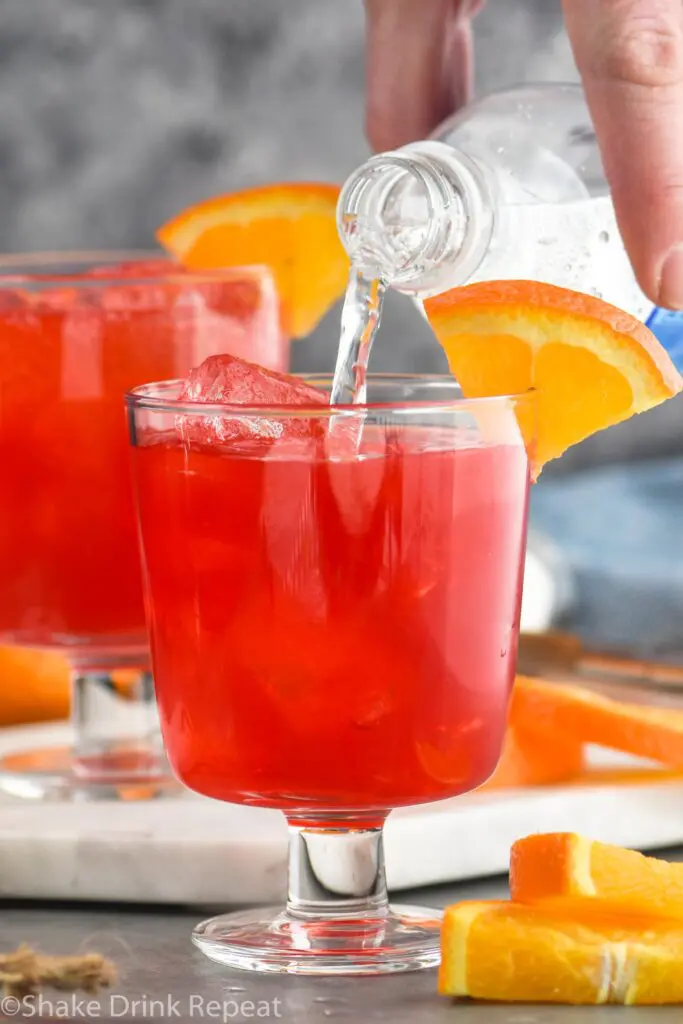 two glasses of sloe gin fizz recipe ingredients with orange slice garnish and club soda poured