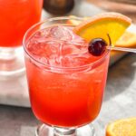 two glasses of slow gin fizz with orange slice and cherry garnish and jigger