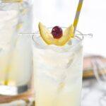 glass of tom collins with ice, lemon and cherry