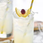 glass of tom collins with ice, lemon, and cherry