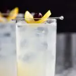 glass of tom collins with ice, lemon, and cherry