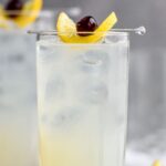 two glasses of tom collins drink with ice, lemon, cherry