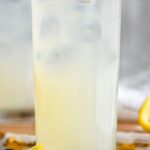 glass of tom collins cocktail with lemon and cherry