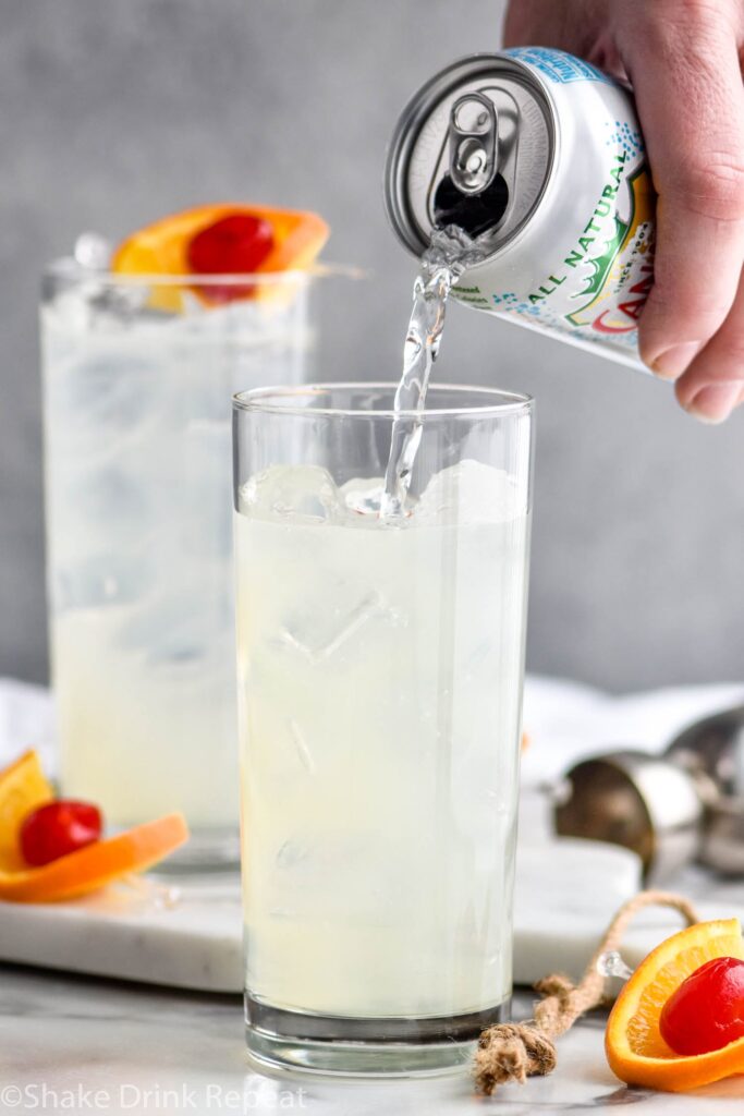 two glasses of vodka collins recipe with soda water, ice, cherry and orange garnish