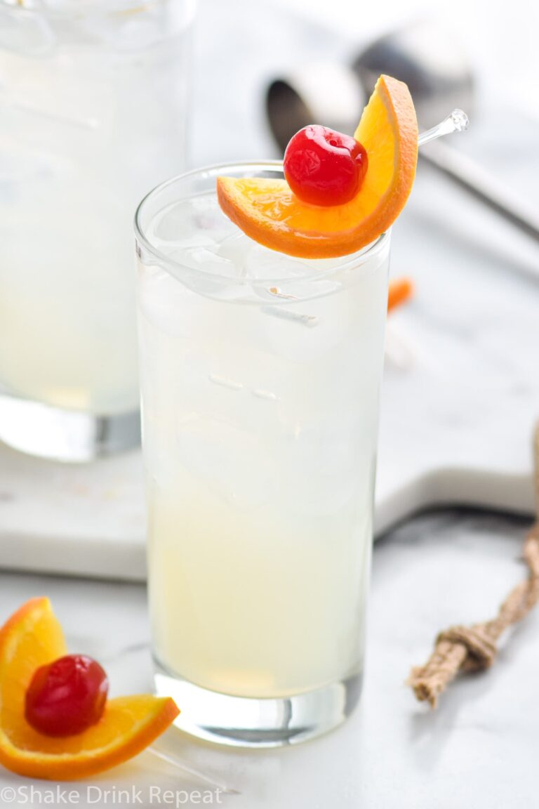 glass of vodka collins with ice, orange slice and cherry