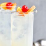 two glasses vodka collins with ice, orange, and cherry