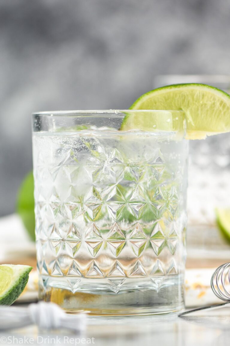 glass of vodka tonic cocktail with ice and lime wedge